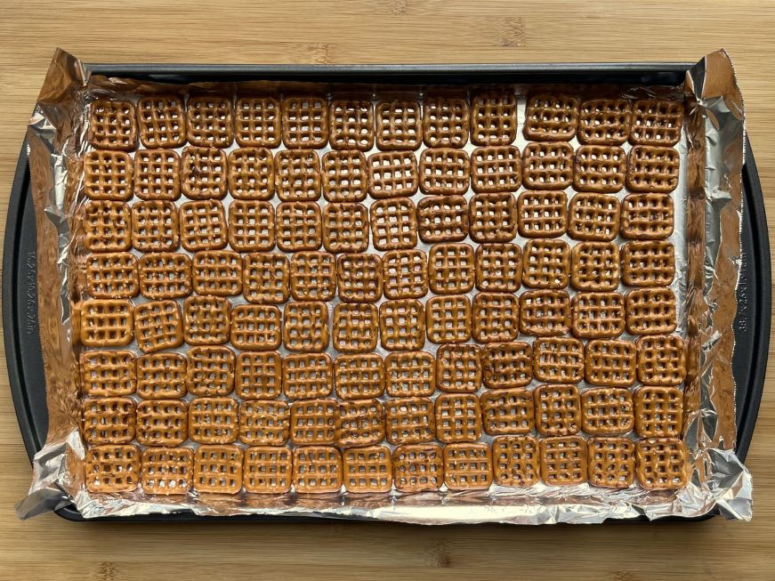 Foil lined pan with rows of pretzels