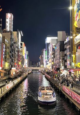 Boat in a canal with neon-lit buildings on either side