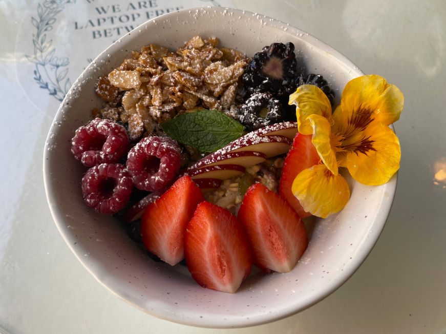 Alpine muesli, Dilly Dally Coffee Cafe Bowl of muesli toppped with fresh berries, almonds, and a flower