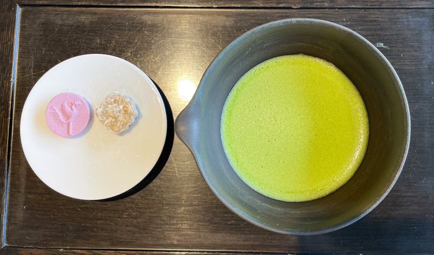 Bowl of matcha tea with a plate with two small cookies