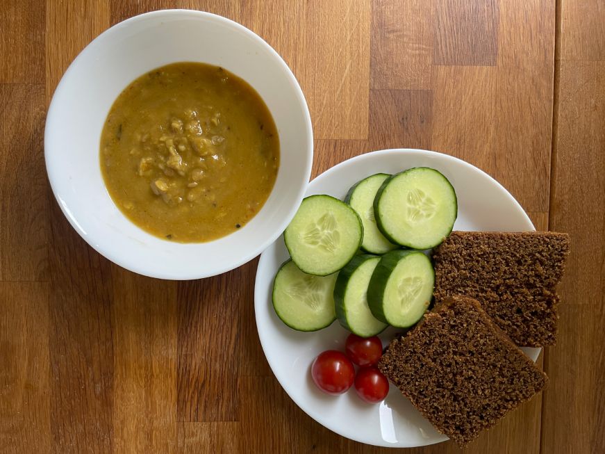 Dinner at our Airbnb Bowl of soup and plate with sliced bread, cherry tomatoes, and sliced cucumbers