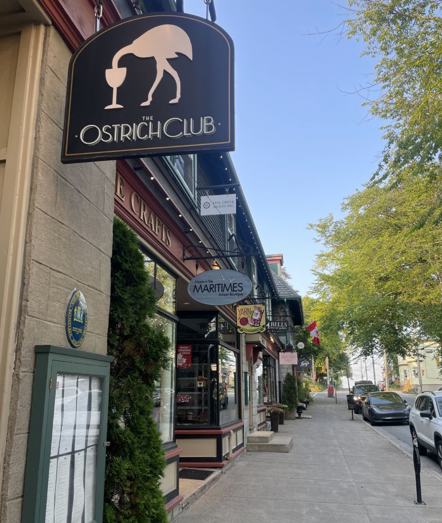 Hydrostone neighborhood The Ostrich Club sign with a row of shops in the background