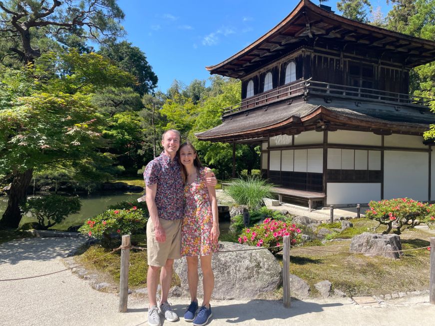 Stacy and Mike standing in a temple garden with a building in the background