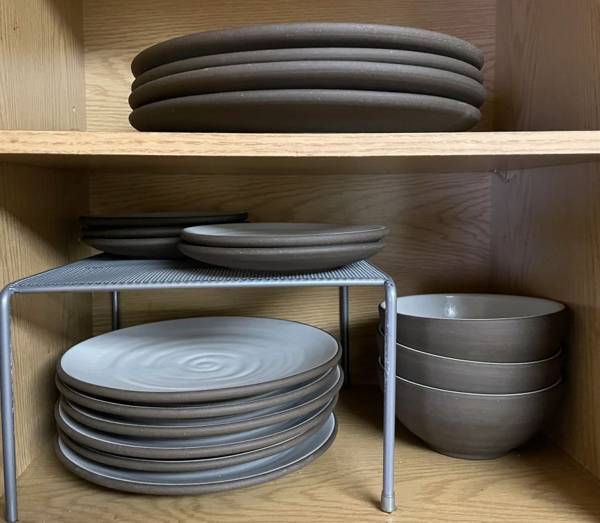 Plates of varying sizes and bowls in a cupboard