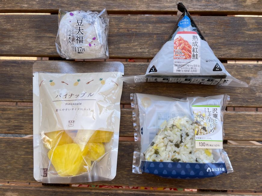 Two packaged onigiri, a package of fresh cut pineapple, and a packaged mochi