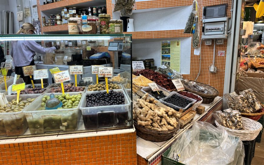 Market stall with large bins filled with different types of olives