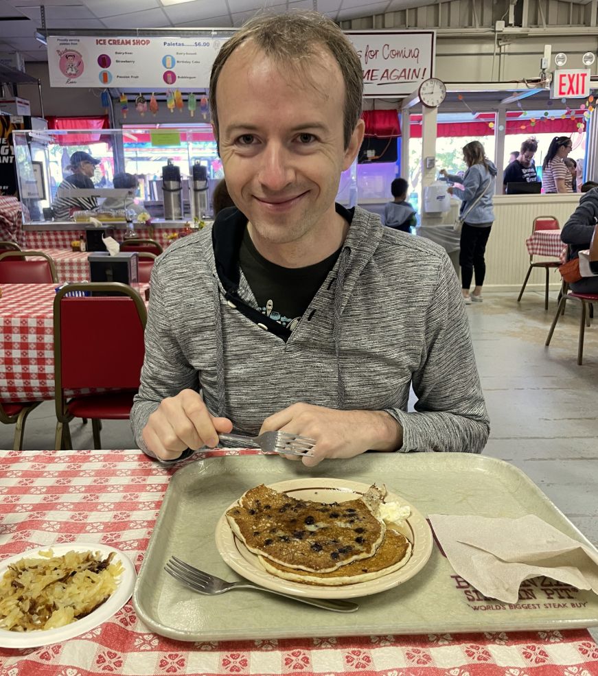 Mike sitting at a table eating a large blueberry pancake