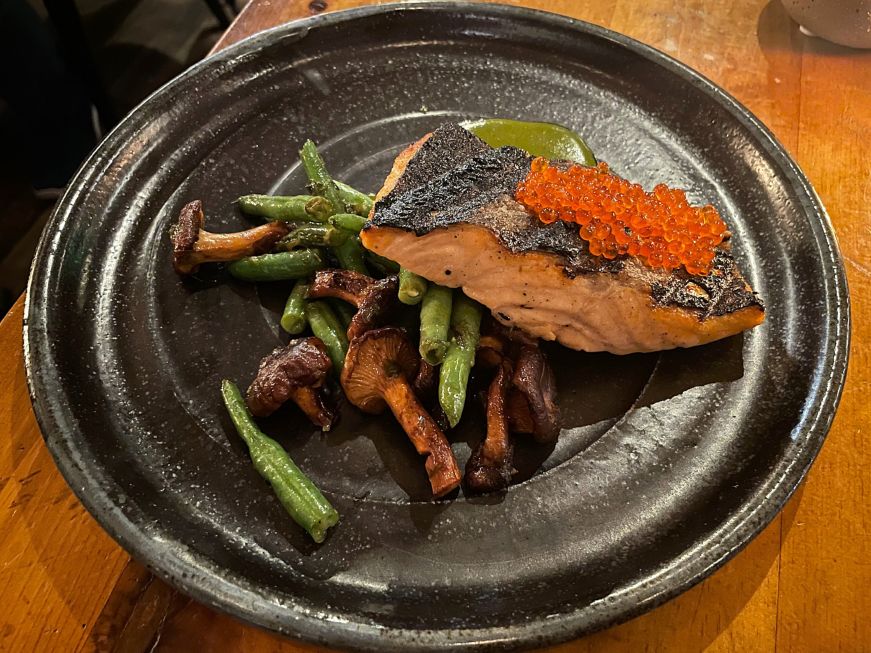 Plate with green beans, mushrooms, and a piece of salmon topped with orange-colored caviar