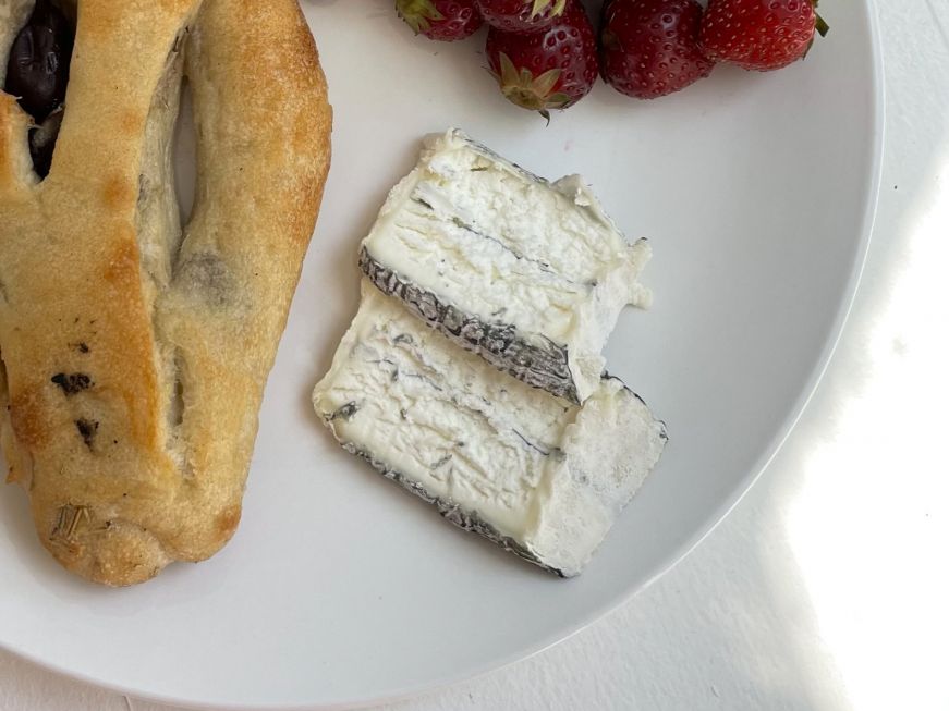 Two slices of ash-coated goat cheese on a plate