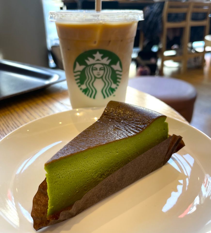 Piece of matcha cheesecake with a Starbucks cup of iced coffee in the background