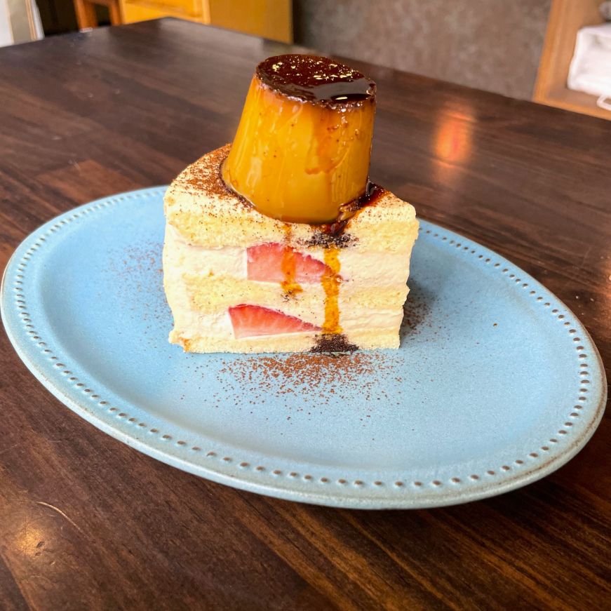 Piece of strawberry layer cake topped with a small panna cotta