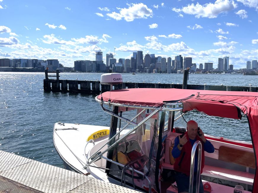 Small boat in the foreground with Boston Harbor in the background