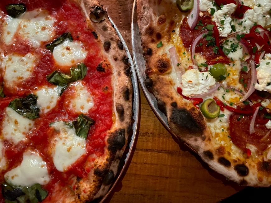 Top down view of two wood-fired pizzas