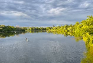 Lake surrounded by trees with the Minneapolis skyline in the background